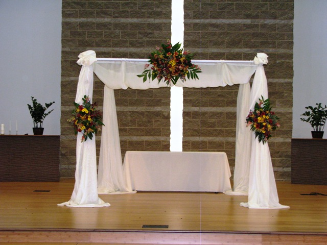 Iron square arch with white draping and flower
